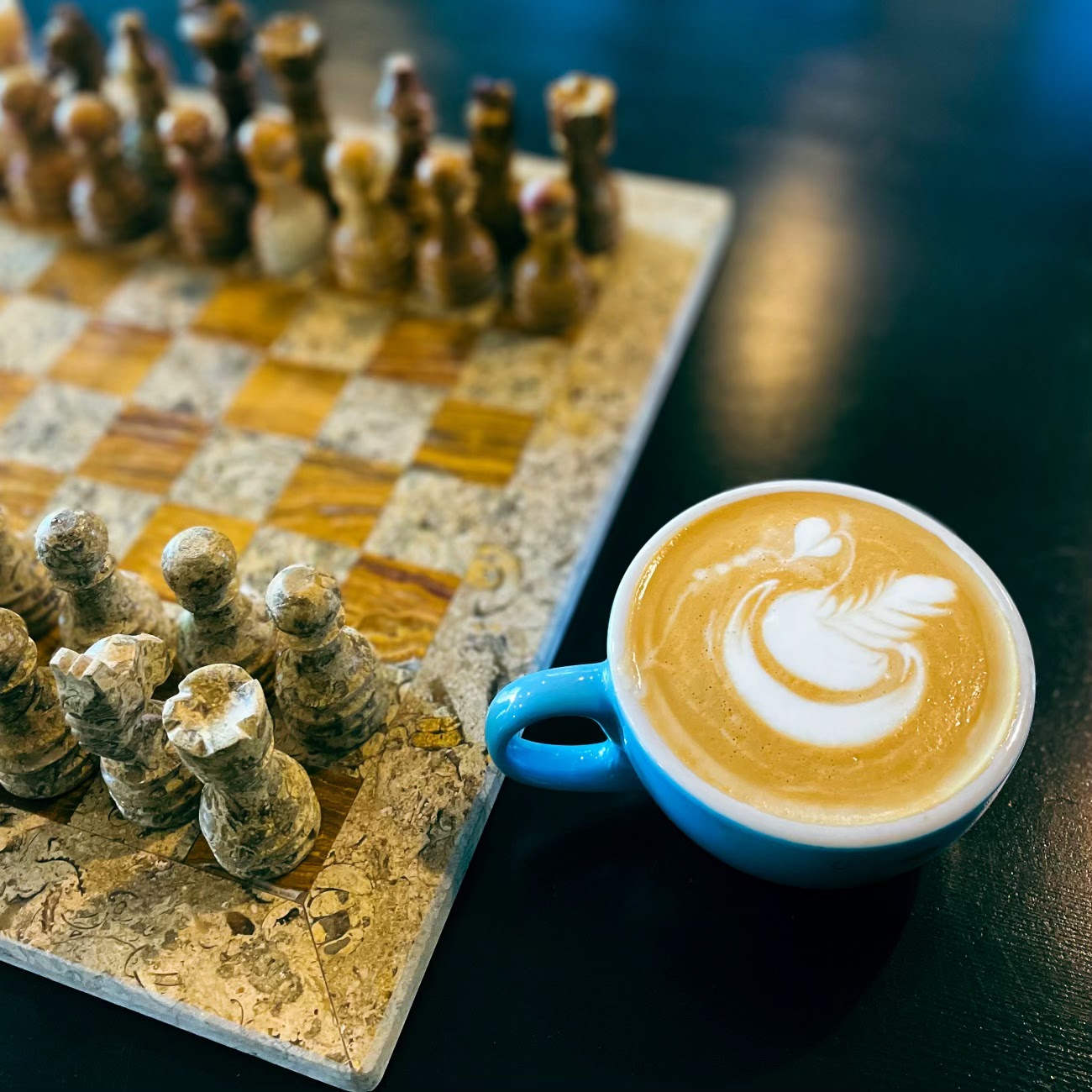 Blue cup of coffee beside a tabletop game
