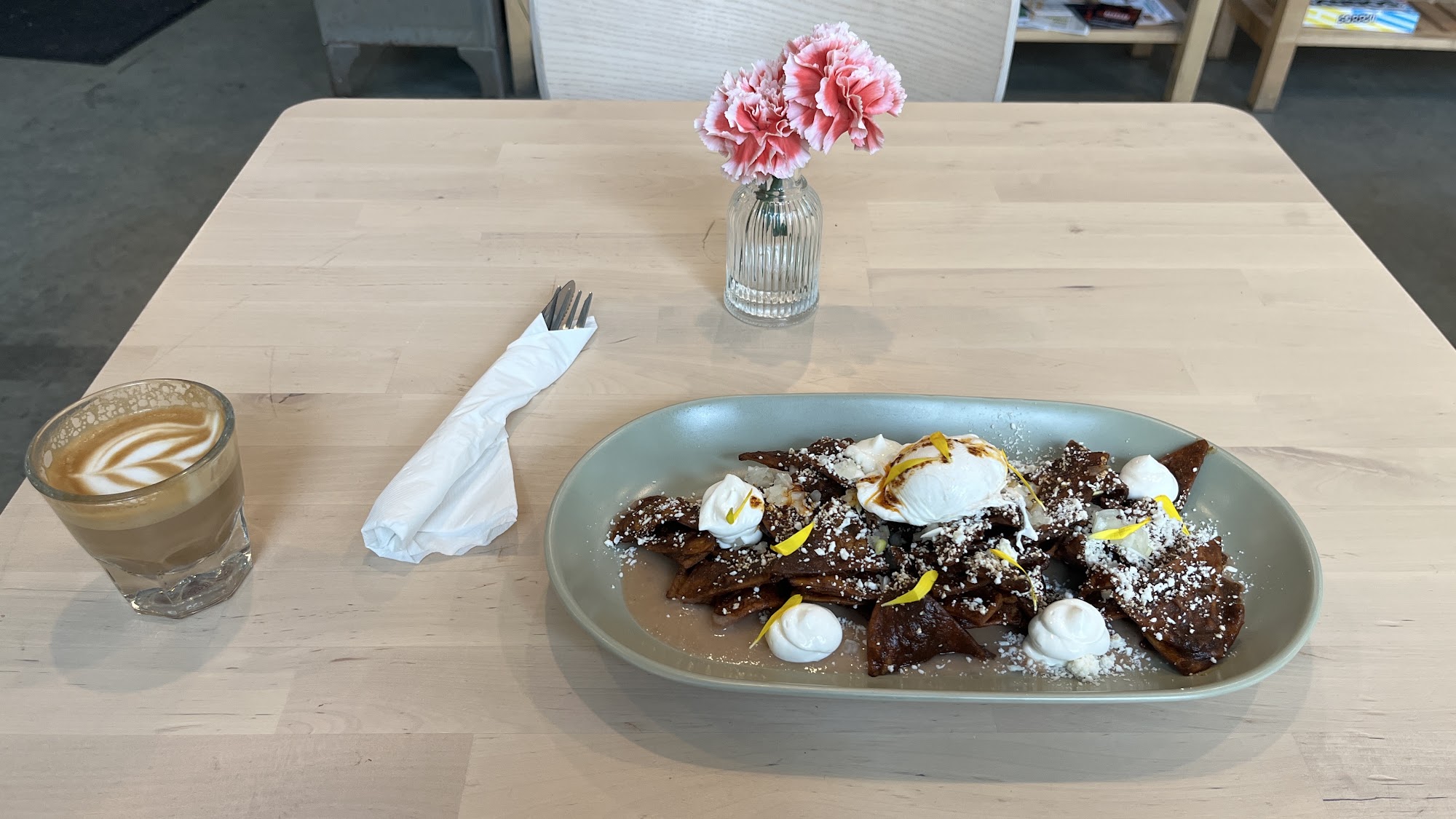 Plated dish with coffee, flowers, and utensils on a cafe table